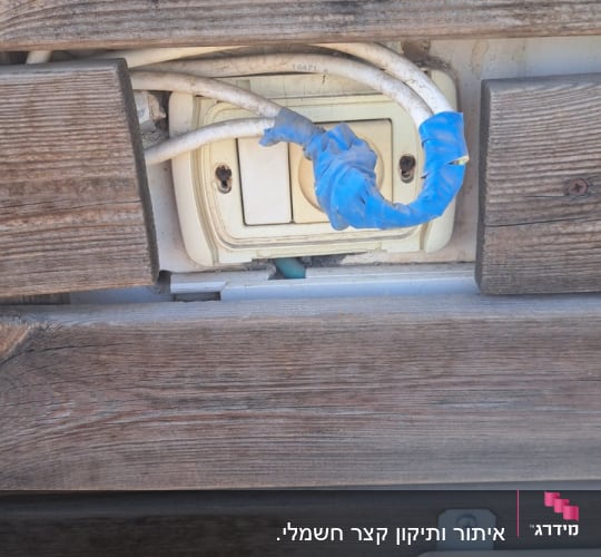 שקע חשמל עם חוטים עטופים בסרט כחול